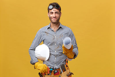 pleased-dirty-man-worker-having-protective-goggles-head-holding-rolled-paper-with-hardhat-isolated-yellow-wall-professional-handsome-male-with-belt-tools-going-work2